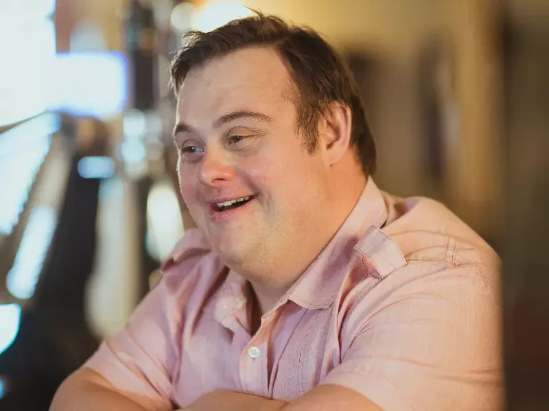 Happy man with down syndrome smiling and looking past the camera